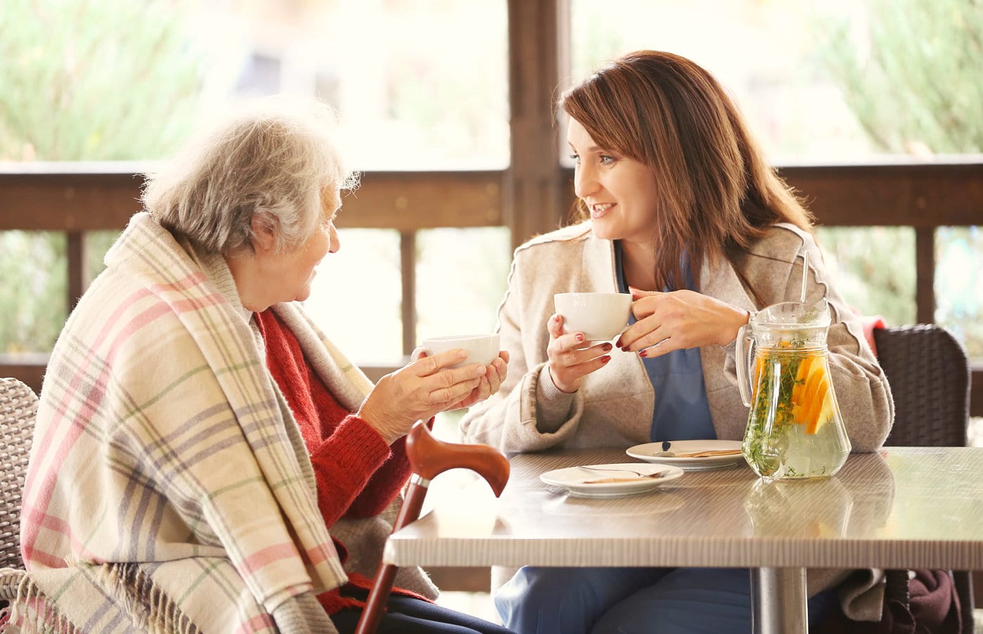 caregiver and senior woman having tea